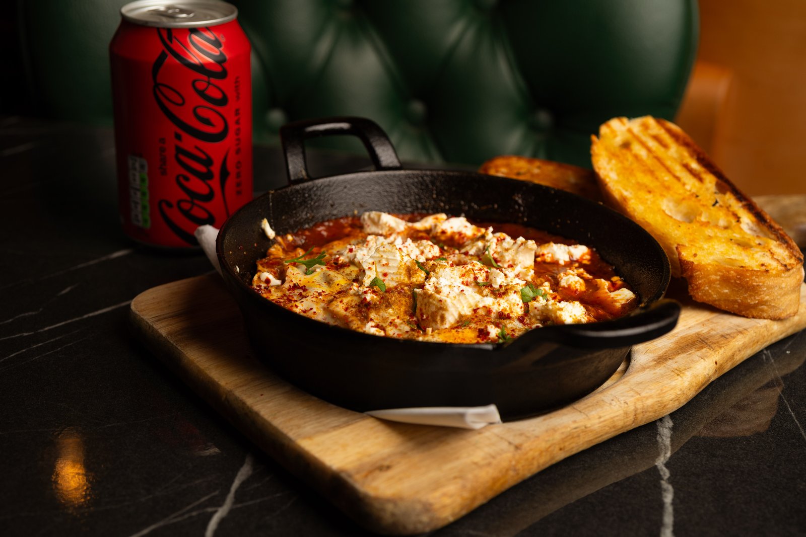 Mediterranean shakshuka with feta in a cast-iron pan, grilled sourdough on the side, in the Rendezvous Caffe green booth