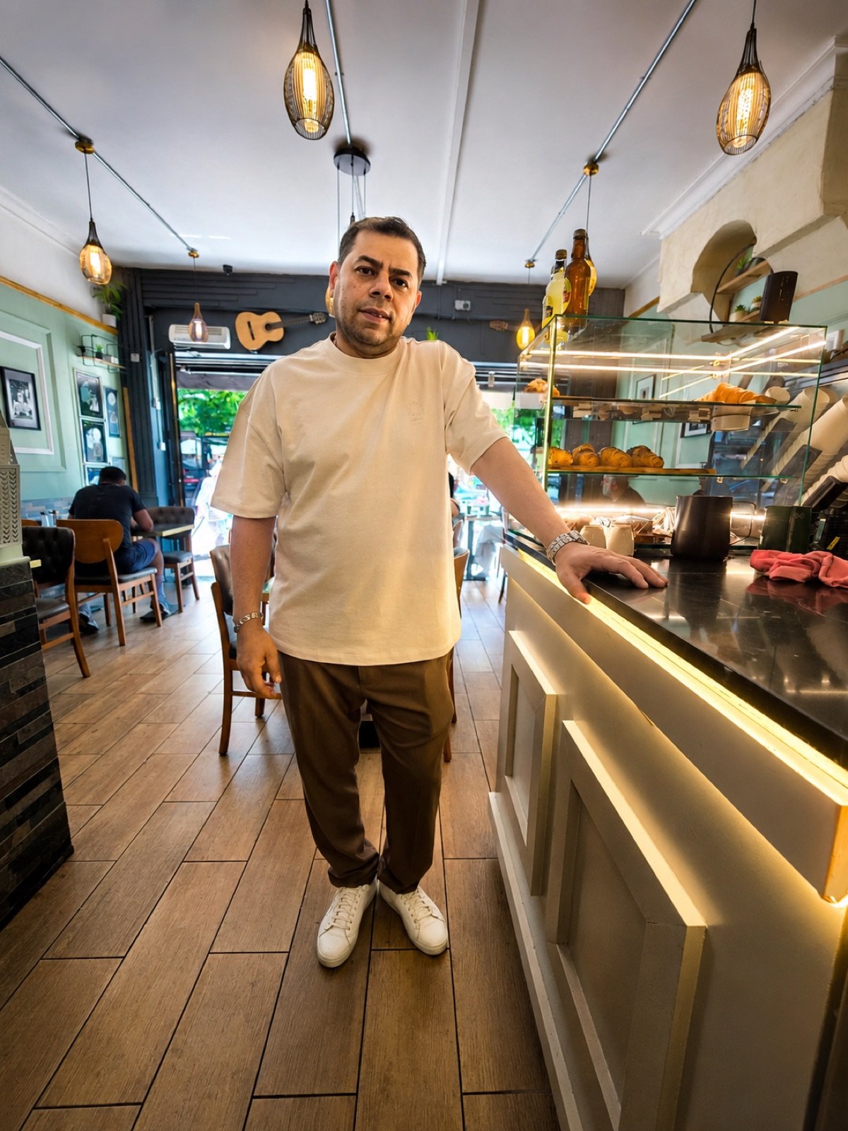 Sam, owner of Rendez-Vous, standing beside the counter inside the cafe
